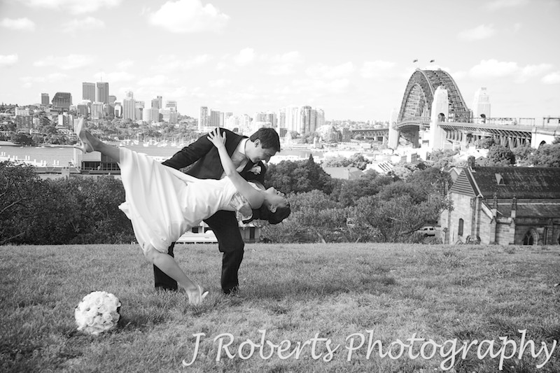 Groom dipping bride with Sydney Harbour and bridge in the background on Observatory Hill - wedding photography sydney